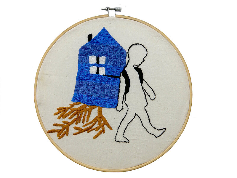 Stickerei, eine Figur trägt ein Haus mit Wurzeln, die herausgerissen sind.